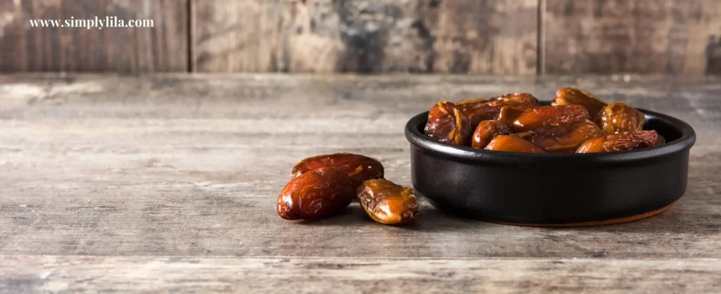 Medjool dates in a black bowl on a rustic wooden table