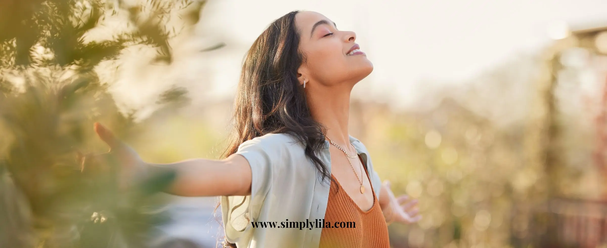 Woman standing outdoors with arms open practicing gratitude and mindfulness